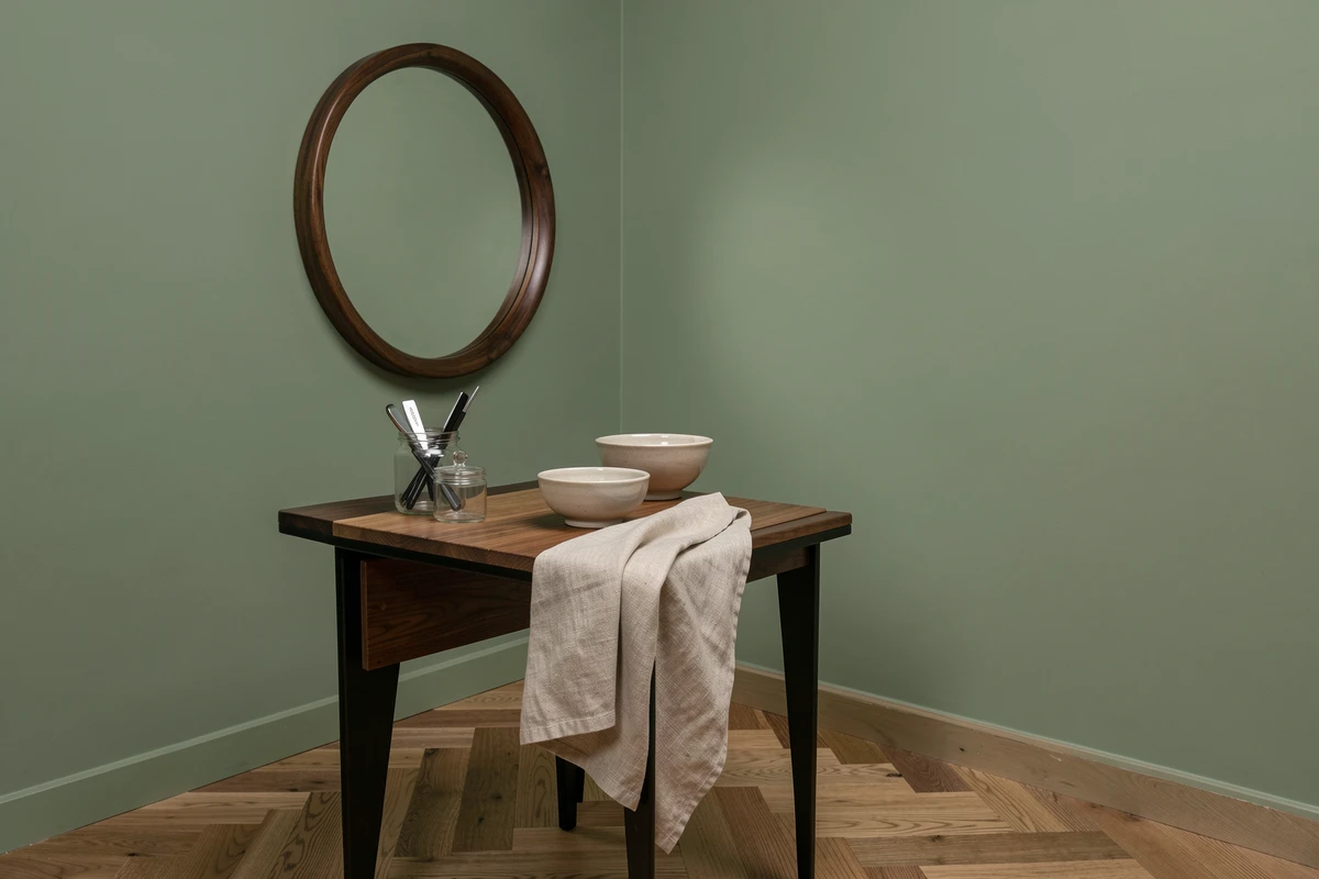 Coin de salon de coiffure masculin au style mid-century moderne avec mur vert sauge, miroir en noyer et station de travail épurée