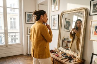 Femme aux tresses box braids en chignon devant un miroir dans un appartement parisien, illustrant la polyvalence du tissage