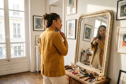 Femme aux tresses box braids en chignon devant un miroir dans un appartement parisien, illustrant la polyvalence du tissage