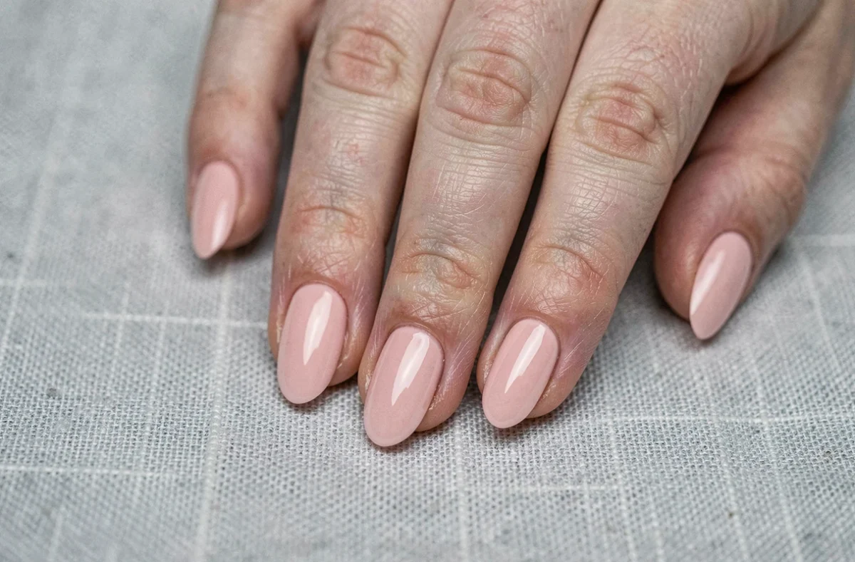 Résultat final d'une pose américaine sur des ongles rongés avec finition gel nude rose brillant